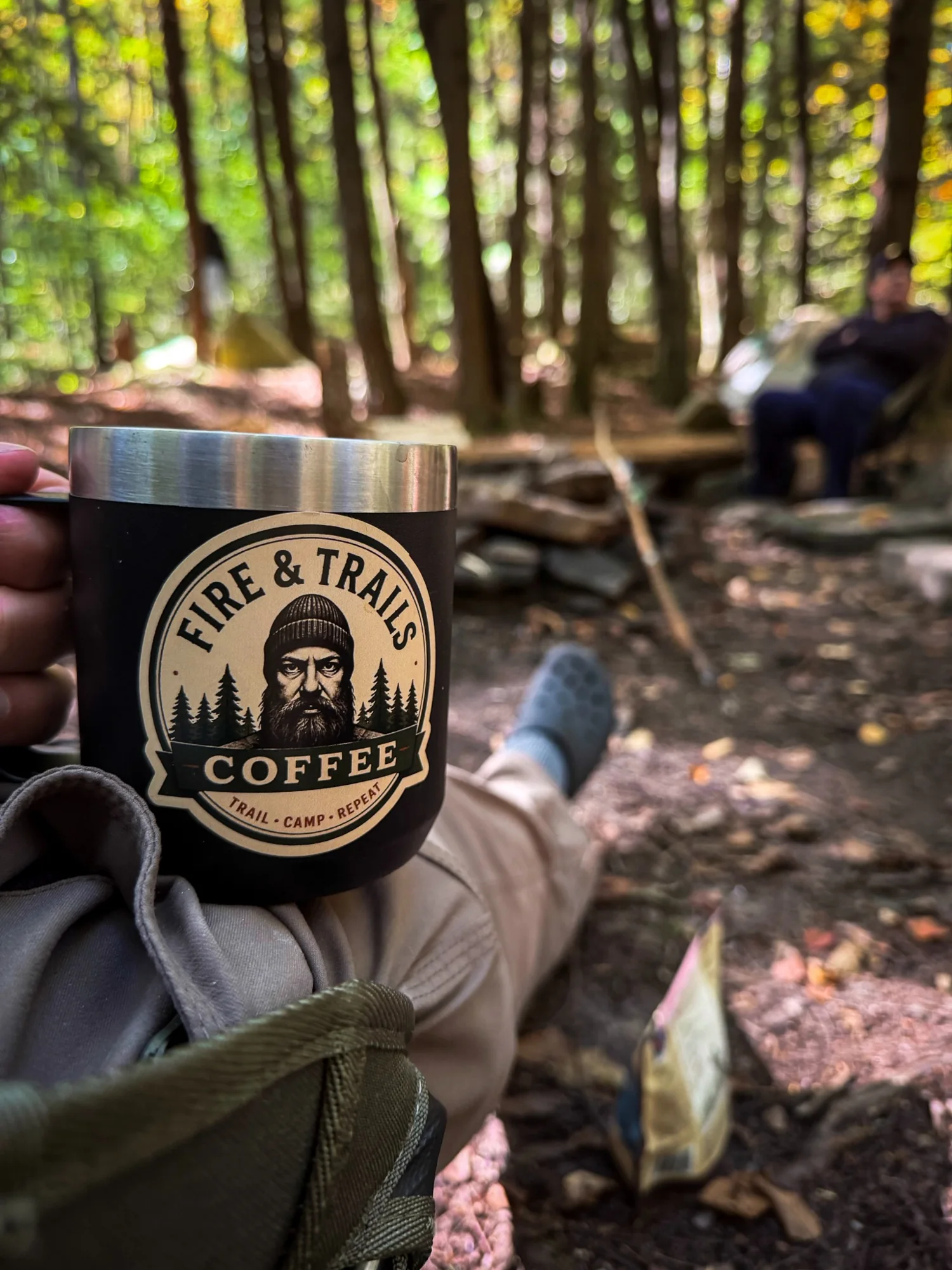 A Fire & Trails coffee mug held during a quiet break in the forest